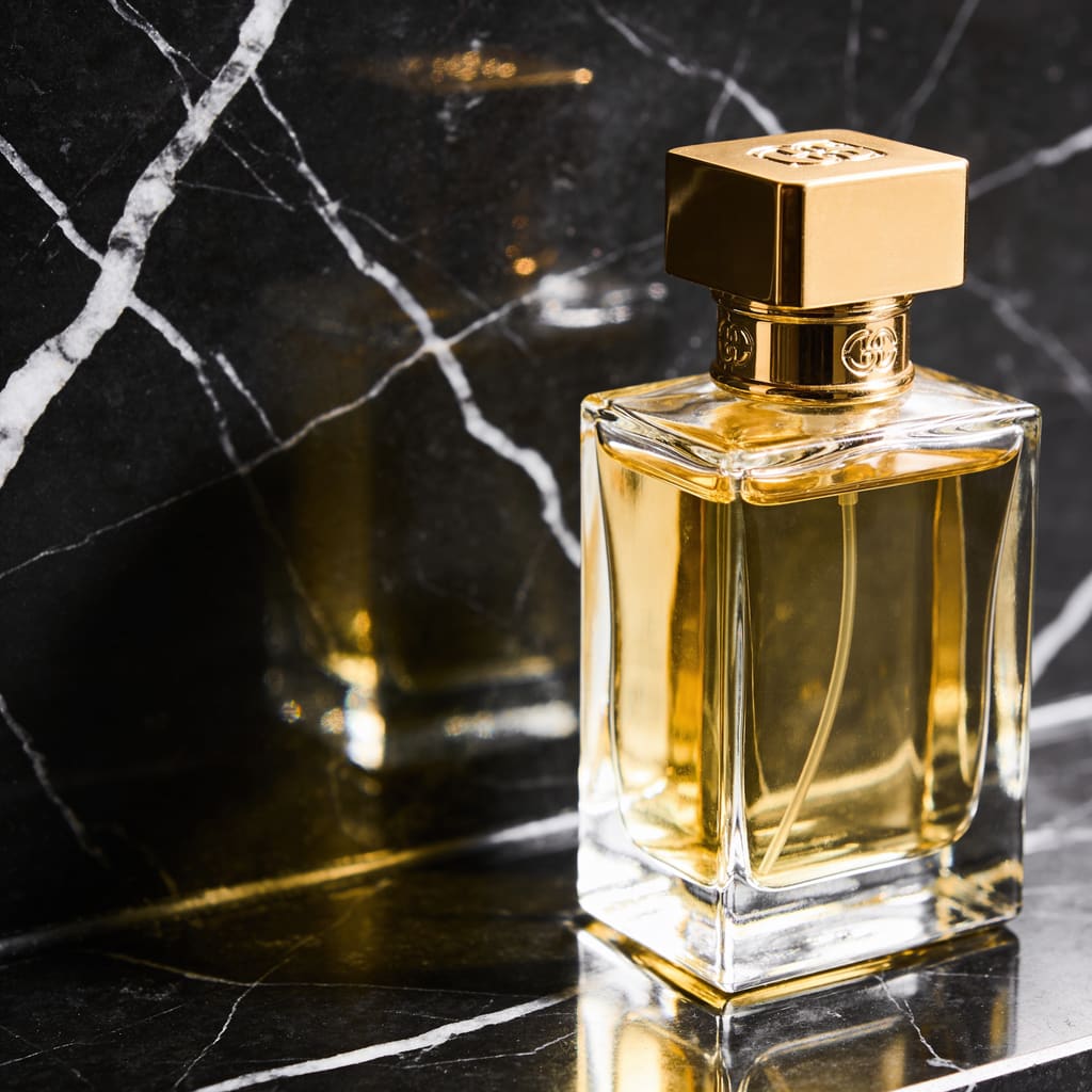 A luxury perfume bottle on polished black marble, soft studio lighting, gold reflections, product photography